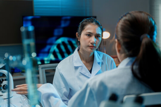 Two female medical researchers having a discussion about scientific data displayed on a computer screen in a laboratory setting