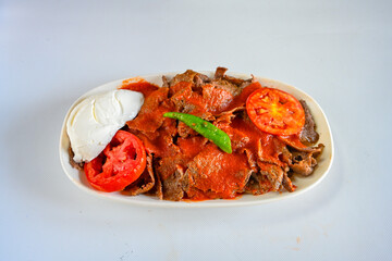 Turkish  Traditional Ramadan doner kebab with tasty tomato sauce and rice or turkish pilav in white plate on table background. Lavash doner kebab ( doner zurna durum )  Pilavustu doner Iskender kebap