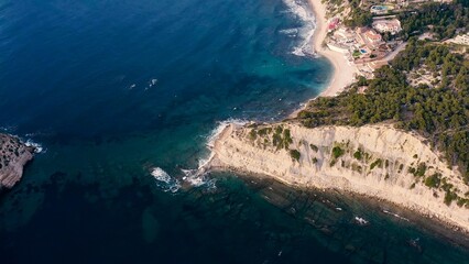 Aerial view of San Martin Cape, with the islet and beach of Portichol, in the Mediterranean coast of Javea, Alicante, Spain.