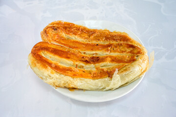 Turkish style meat stuffed filo dough borek served kol boregi.Cheese and minced pie are sliced on a marble background. Turkish name: Kol Boregi, kiymali, peynirli su boregi. Ci borek. Kafkas cig borek