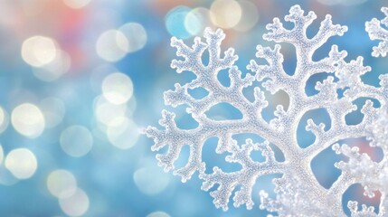 Close-up of a delicate, white snowflake ornament against a blurred, pastel blue bokeh background.