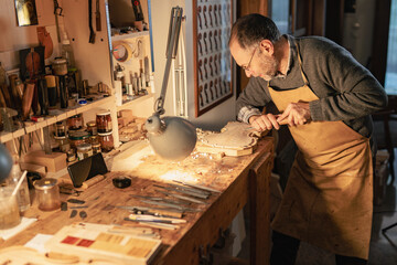 Luthier carefully carving violin wood in cremona workshop