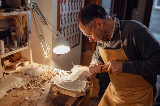 Italian violin maker crafting violin in cremona workshop