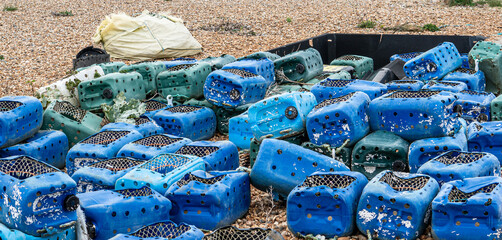 Abandoned blue lobster pots and cans left out on the seaside beach showing pollution environmental waste due to lack of preservation investment