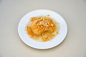 Pistachio kadayif on a plate. Turkish Dessert Kadayif with pistachio powder. Local name burma kadayif, antep fistikli, cevizli kadayif .
