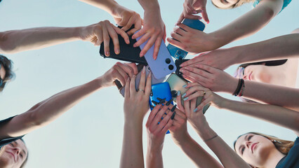 High school students forming a circle with their smartphones, representing togetherness, sharing,...