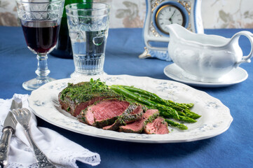 Barbecue sliced roast beef with green asparagus served as close-up on a classic design plate with red wine
