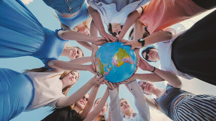 Earth conservation concept. 10 girls and boys surround the rotating earth globe with their palms A view in motion.