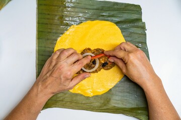 Preparing a Venezuelan hallaca with ingredients being added by hand.