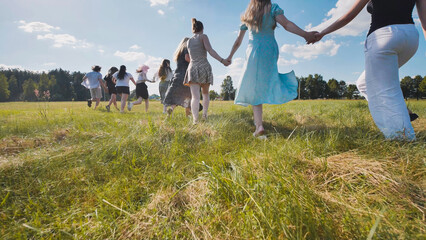 High school students running through a meadow, joyfully marking the end of the school year in summer