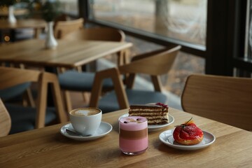 Aromatic coffee and delicious desserts served on wooden table in cafe