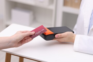 Woman paying with credit card via terminal at counter indoors, closeup