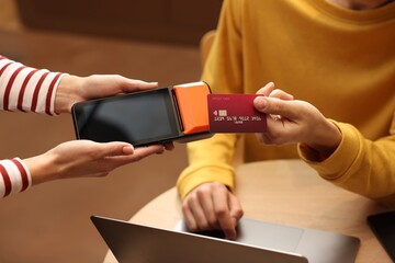 Man paying with credit card via terminal in cafe, closeup