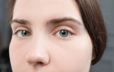 Fototapeta premium Closeup view of young woman with beautiful blue eyes on grey background