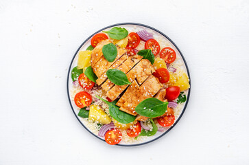 Nourishing salad with grilled chicken, couscous, tomatoes, onion, spinach and orange. White background, top view