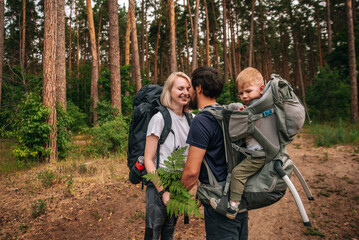 Happy family on a hike with a child in a travel backpack. laugh, smile, get together and have a...