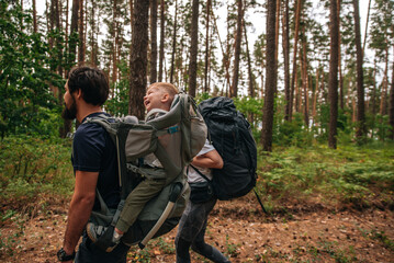 Happy family on a hike with a child in a travel backpack. laugh, smile, get together and have a...