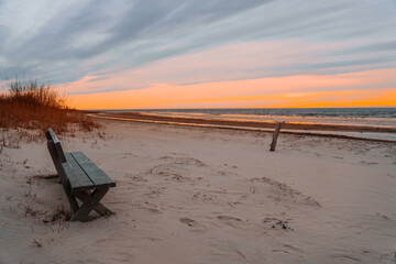 empty wooden bench on the seashore at sunset