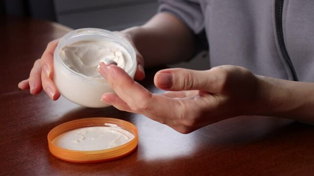 Female hands applying hand cream. Hand massage. Close-up.