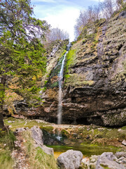 Una cascata immersa nella natura incontaminata, circondata da muschio verde brillante e foglie...