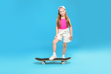 Little girl with skateboard on light blue background