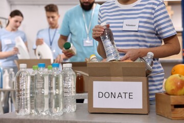 Group of volunteers packing donation goods indoors, closeup