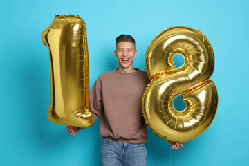 Coming of age party - 18th birthday. Happy young man with number shaped balloons on light blue background