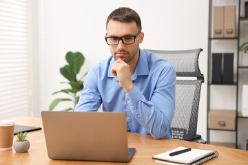 Programmer working on laptop at wooden desk indoors