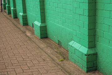 Fototapeta premium Old grunge street. Grungy urban background of a brick wall painted in ugly green