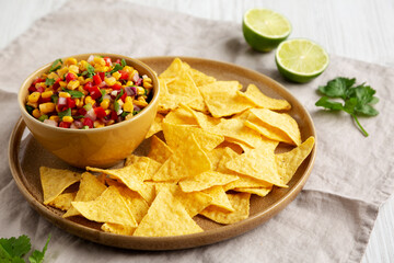 Homemade Corn Salsa with Tortilla Chips on a Plate, side view.