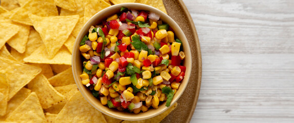 Homemade Corn Salsa with Tortilla Chips on a Plate, top view. Flat lay, overhead, from above.