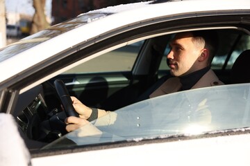 Driver behind steering wheel of modern car, view from outside