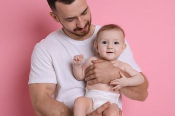 Father with his cute baby on pink background