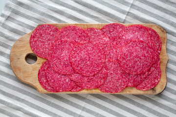 Sliced Spanish Salami Extra on a wooden board, top view. Flat lay, overhead, from above.