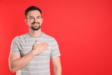 Man making promise on red background, space for text. Oath gesture