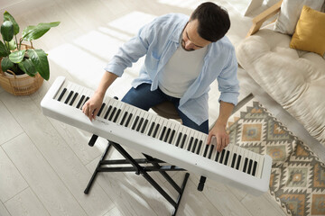 Man playing synthesizer at home, above view