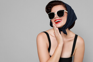 Pin-up woman in sunglasses on grey background, space for text