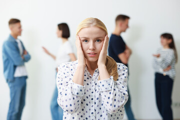 Young woman feeling uncomfortable among people indoors, selective focus