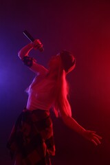 Fototapeta premium Talented singer performing on dark background with color lights