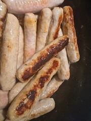 Pile of raw and browned chipolata sausages