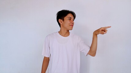 handsome asian young man wearing white shirt smiling while looking to the side and gesturing...