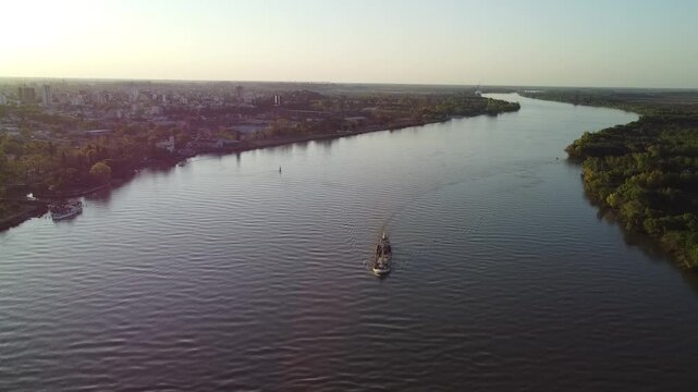 Cargo ship sailing peacefully along the Parana near Zarate with a view of the city at sunset