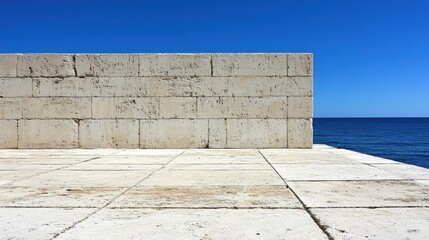 Architectural Minimalism Featuring a Textured Stone Wall Overlooking a Calm Azure Sea Under a Clear Blue Sky with Crisp Concrete Tiles in Perspective