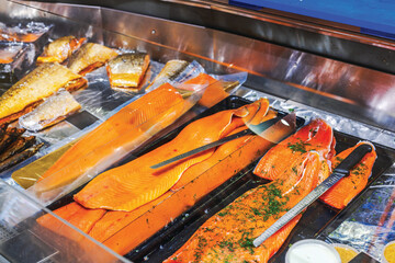 Fresh salmon fillets and smoked fish displayed on ice at seafood counter in grocery store. Sweden.