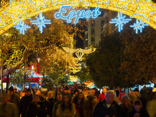 Illuminated Christmas market with Ermou street sign, crowded with shoppers under bright decorations, Athens, Greece