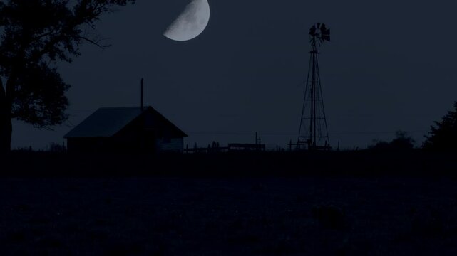 Tilt shot of the moon rising or setting over an abandoned farm at night in South Dakota.