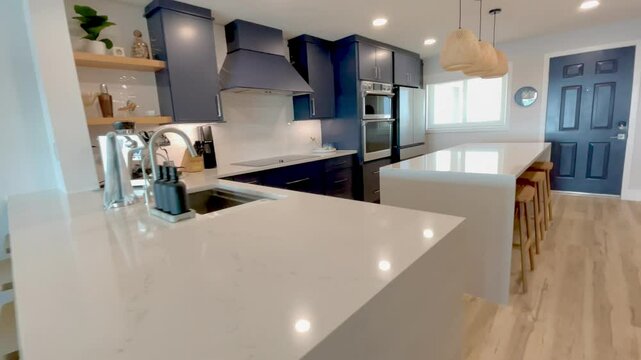 Vertical short video of a modern coastal condo kitchen with blue cabinets, White Island, and beachy wood accents.