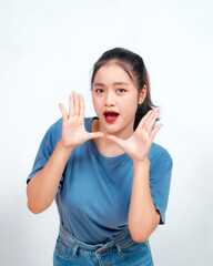 Surprised Asian woman reclines on her hands and shouting while looking at the camera over white background