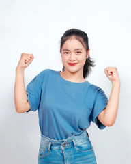 Overjoyed young Asian woman is raising her hands in the air with happy successful expression