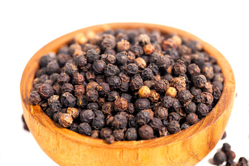 Black peppercorns (black pepper) in a wooden bowl isolated on a white background